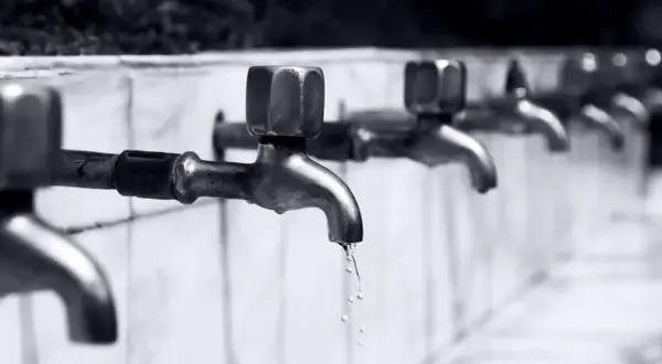 Reihe von Wasserhähnen, aus denen Tropfen fallen.