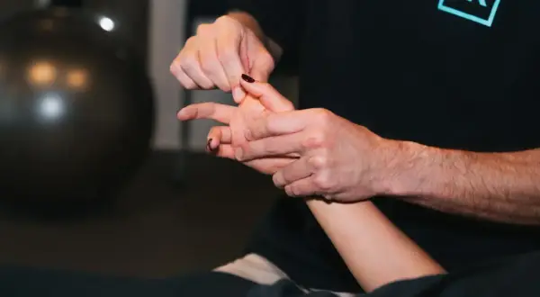 Un thérapeute manipule délicatement un doigt, peut-être pour traiter une luxation.