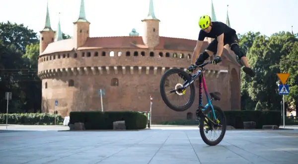 Kaskader na rowerze wykonuje trik przed Barbakanem w Krakowie. To niesamowity pokaz velo kraków!