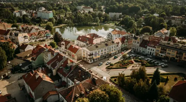 Urokliwe Mrągowo z lotu ptaka. Jezioro, kolorowe kamienice i zielone dachy tworzą malowniczy krajobraz. Odkryj mrągowo atrakcje!