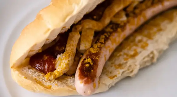Ein Brötchen mit Wurst, Ketchup und Currypulver, wie bei einem bosna rezept.