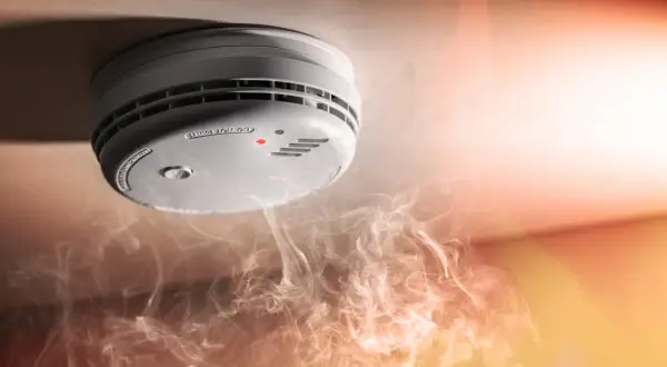 Détecteur de fumée au plafond, avec une petite lumière rouge allumée. Comment savoir si mon détecteur de fumée fonctionne ? La fumée tourbillonne en dessous.