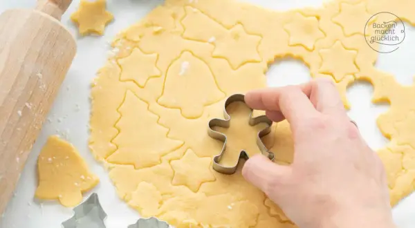 Mit diesem Kekse Rezept entstehen Sterne, Tannenbäume und Lebkuchenmännchen. Ein Holz-Nudelholz liegt daneben.