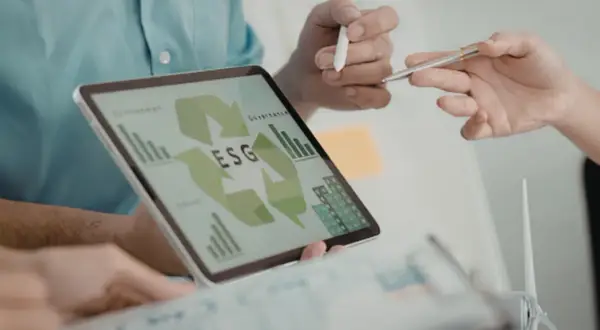 Zespół analizuje dane ESG na tablecie, planując strategię zrównoważonego rozwoju. To kluczowy element nowoczesnego system zarządzania energią ems.