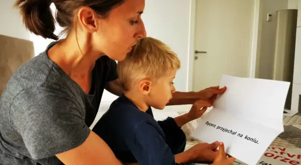 Mama czyta synkowi, kiedy czytać dziecku to ważny moment. Na kartce napisano "Rycerz przyjechał na koniu".
