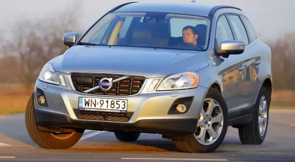Srebrny Volvo XC60 z kierowcą na drodze. Sprawdź aktualną volvo xc60 cena i oferty.