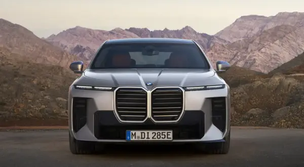Nowe BMW Serii 7, z imponującym grillem i nowoczesnymi światłami, prezentuje się na tle górskich krajobrazów. Sprawdź jego BMW 7 cenę.