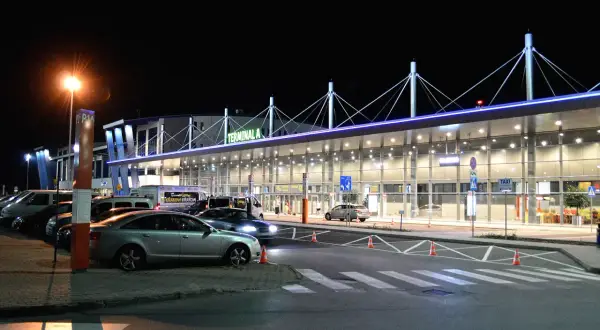 Dojazd z dworca PKP do Katowice-Pyrzowice. Terminal A lotniska nocą, zaparkowane samochody i autobus.