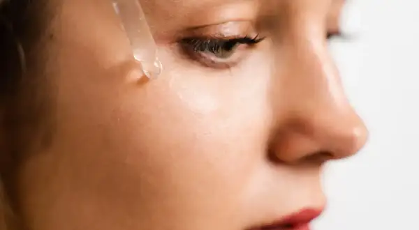 Ein Tropfen hochdosiertes Hyaluron Serum fällt auf die Haut.