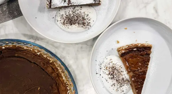 Två tallrikar med glutenfria havrekakor med kardemumma och grädde. En hel kaka i en glasform.