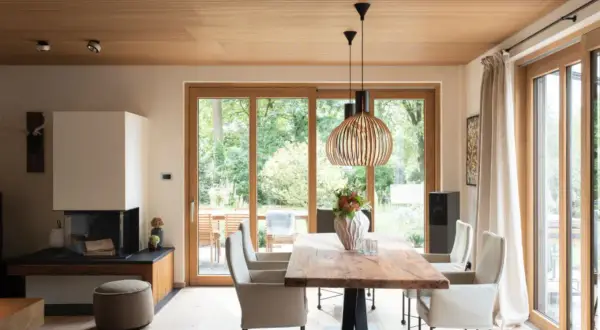 Moderne Inneneinrichtung mit viel Holz: Essbereich mit Holztisch, Kamin und großen Glasfronten zur Gartenseite.
