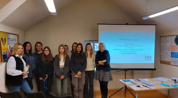 Grupa osób na tle ekranu projekcyjnego w Miejskim Ośrodku Pomocy Społecznej w Lublińcu.