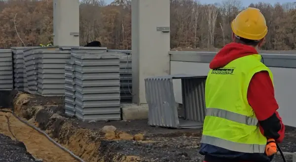 Pomocnik elektryka w kamizelce odblaskowej na budowie.