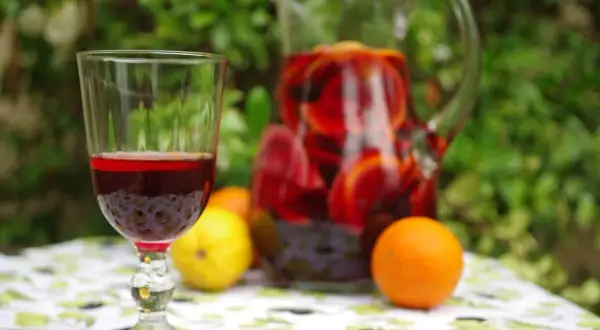 Orzeźwiająca sangria wino z owocami w dzbanku i kieliszku, obok pomarańcze i cytryna. Idealna na letnie popołudnie.