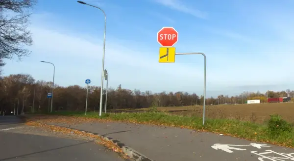 Znak STOP i znak informujący o drodze z pierwszeństwem łamanym. Na ścieżce rowerowej namalowane symbole pieszych i rowerzystów.