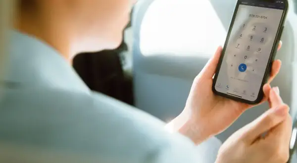 Osoba w samochodzie wybiera numer na telefonie, pokazując, jak działa voip.