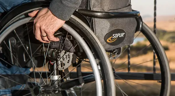Dłoń na obręczy wózka, symbolizująca codzienne życie z tetraparezą spastyczną.