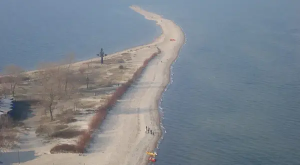 Półwysep w Rewie z krzyżem i plażą. Atrakcje turystyczne tego miejsca przyciągają spacerowiczów.