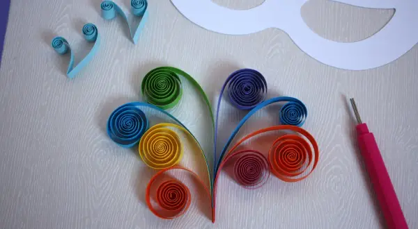 Creazione di maschere carnevale fai da te bambini con strisce colorate in quilling. Un progetto creativo per decorare.
