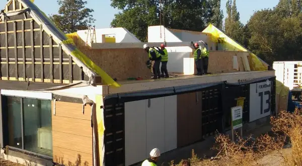 Budowa domu szkieletowego w toku. Pracownicy montują elementy konstrukcji, pokazując, jak samemu zbudować dom szkieletowy.