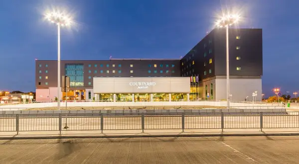 Nowoczesny Courtyard by Marriott, hotel lotniskowy w Warszawie, oświetlony nocą.