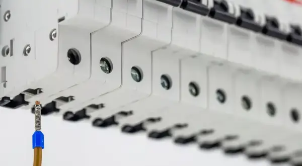 Szczegółowy widok bezpieczników w rozdzielnicy. Zbliżenie na przewód uziemiający. Określenie koszt instalacji elektrycznej.