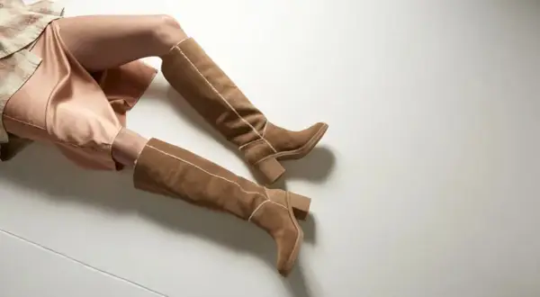 Stivali alti in camoscio marrone con cuciture a contrasto, perfetti per slanciare le gambe corte.