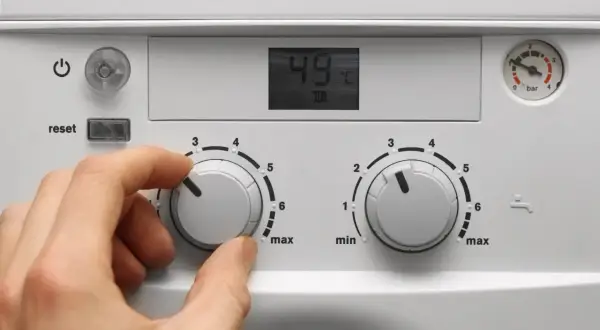Mano che regola la caldaia spenta gas aperto. Il display mostra 49°C.