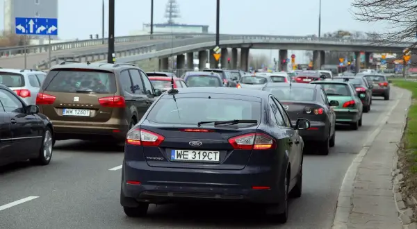 Korki na drodze, kierowcy czekają na zwrot za dojazdy do pracy. Widać rząd samochodów, w tym ciemnogranatowego Forda Mondeo.