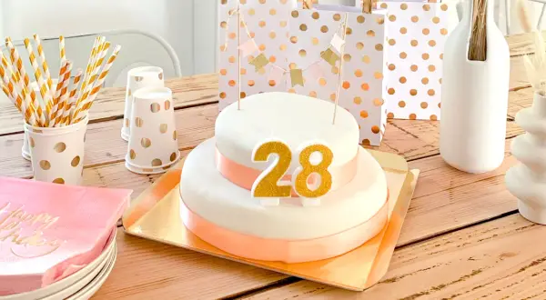Tort urodzinowy z cyframi 28, ozdoby i prezenty na drewnianym stole.