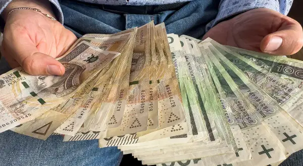 Dłoń trzyma plik banknotów. Czy darowizna a podatek to temat, który Cię interesuje?
