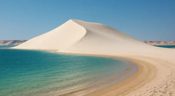 La majestueuse dune blanche de Dakhla rencontre les eaux turquoise d'un lagon paisible, sous un ciel d'un bleu éclatant.