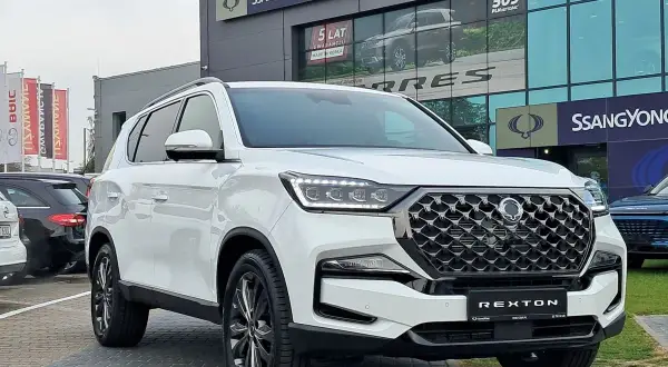 Biały SsangYong Rexton na tle salonu samochodowego. Elegancki SUV gotowy na przygodę.