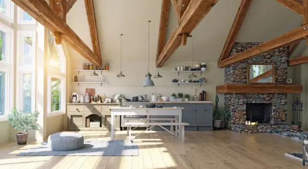 Jasna kuchnia w stylu modern farmhouse z kamiennym kominkiem, drewnianymi belkami i dużymi oknami.