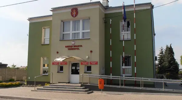 Urząd Miasta Terespol z polską i unijną flagą. Budynek ma zielono-żółtą elewację.