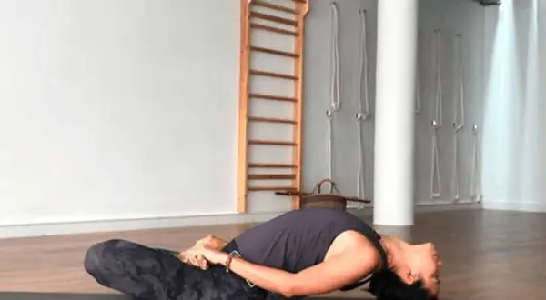 Mujer en postura de yoga Matsyasana, disfrutando de la apertura de pecho yoga beneficios.