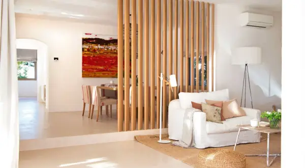 Una solución para como hacer una pared divisoria económica: listones de madera separan el salón del comedor, creando un ambiente moderno y luminoso.
