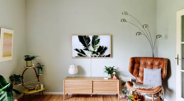 Gemütliche Wohnung mit hellen Farben: Ledersessel, Pflanzen und ein Bild mit Blattmotiv schaffen eine warme Atmosphäre.