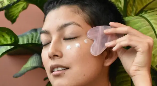 Frau mit Gua Sha Stein und Creme am Auge, genießt die feuchtigkeitsspendende Tremella Wirkung für strahlende Haut.