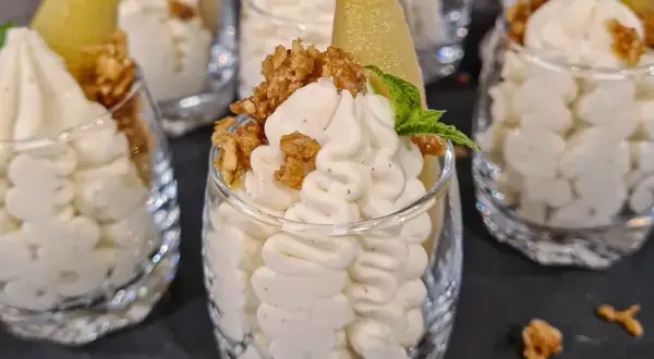 Ljuvlig vispad pannacotta i glas, toppad med krispiga nötter och en bit päron. En perfekt dessert!