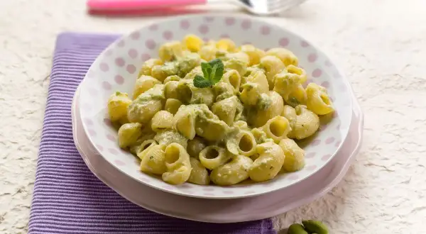 Un piatto di pasta con le fave fresche, condita con una crema verde e guarnita con menta.
