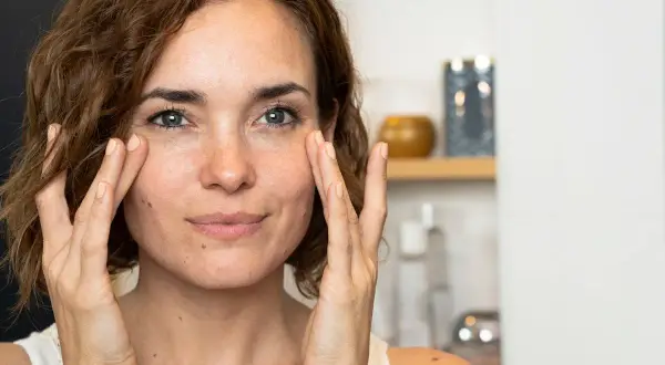 Une femme applique une crème sur son visage, découvrant les premières rides.
