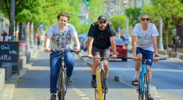 Drei Freunde fahren nebeneinander Fahrrad auf einer Straße.
