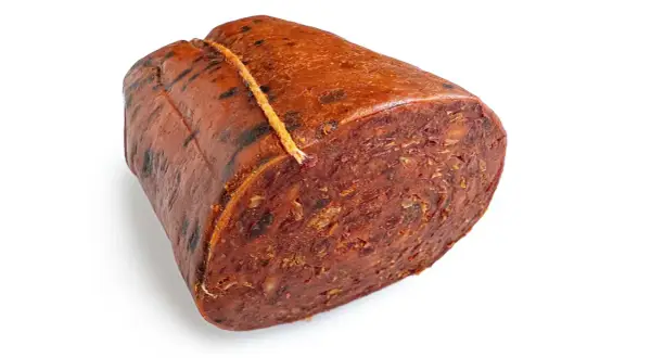 Ein Stück Nduja, eine kalabrische Streichwurst, mit grober Textur und roter Farbe, an einem Faden gebunden.