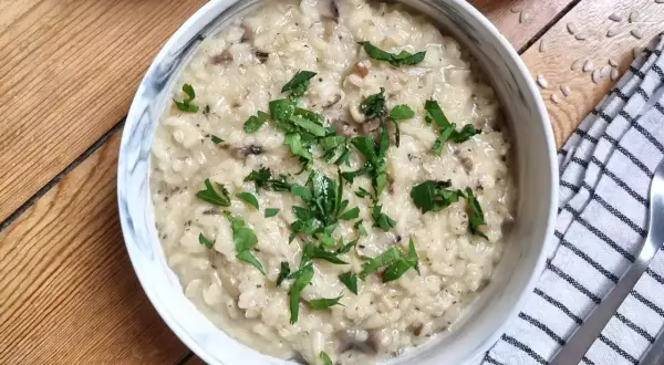 Kremowe risotto z grzybami, przygotowane w Thermomixie, posypane świeżą natką pietruszki. Idealne danie na obiad.