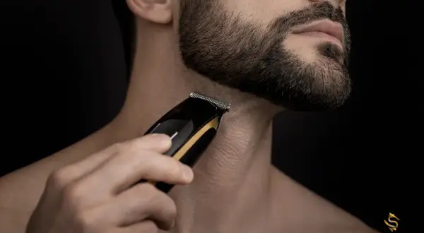 Un homme utilise une tondeuse pour sculpter sa barbe, visant une barbe parfaite.