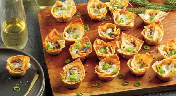 Petits feuilletés croustillants garnis d'effiloché de canard en feuille de brick, parsemés de ciboule et de fromage fondu.