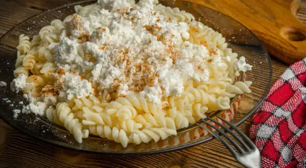 Pyszny obiad z twarogiem na słono: makaron fusilli z dużą porcją białego sera i posypką z papryki.