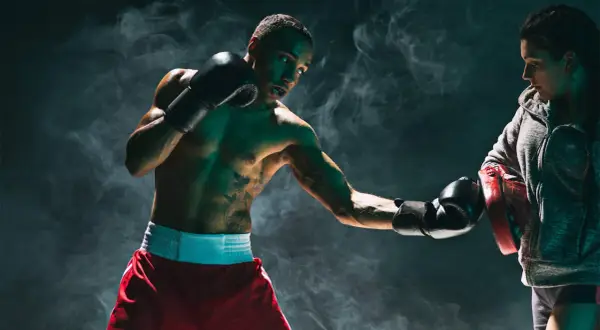 Boxer lands a powerful liver shot during training, smoke swirling around them.