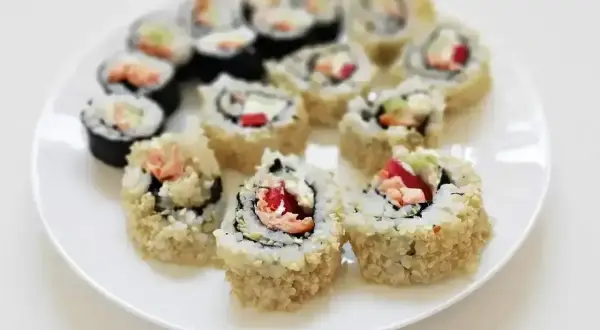 Talerz pełen roladek california sushi, niektóre w chrupiącej panierce z sezamu, kuszą świeżymi składnikami.